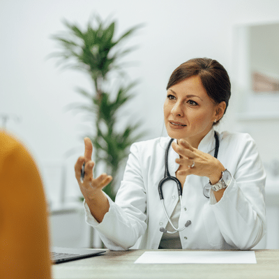 A woman in a white coat talking to a man, representing running a private practice