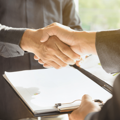 A close-up of a handshake, representing payor contracting and insurance negotiations