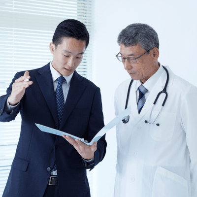 A man in a suit and tie looking at a file with a doctor, representing health system partnership