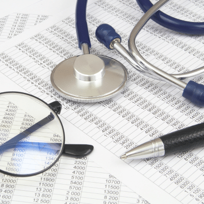 Stethoscope, glasses, pen on spreadsheets, representing launching a new medical practice